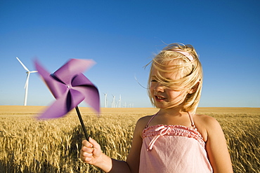 Girl holding pinwheel on wind farm