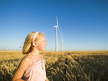 Girl in tall wheat field on wind farm