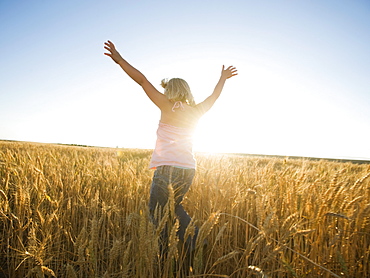 Girl jumping in tall wheat field