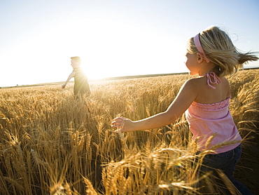 Children running through tall wheat field