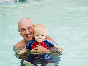 Grandfather and grandson posing in swimming pool