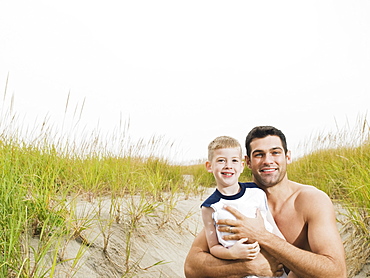 Portrait of father and son hugging on beach