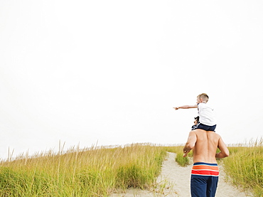 Father carrying son on shoulders at beach