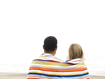 Couple wrapped in towel on beach