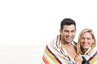 Portrait of couple wrapped in towel at beach