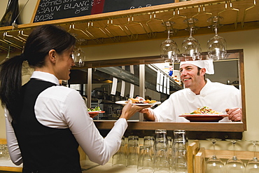 Chef giving waitress plates of food