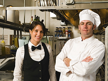 Chef and waitress posing in restaurant kitchen