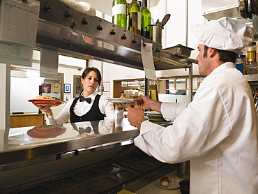 Chef giving waitress plates of food