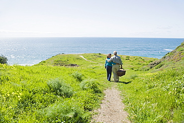 Couple carrying picnic basket to the beach