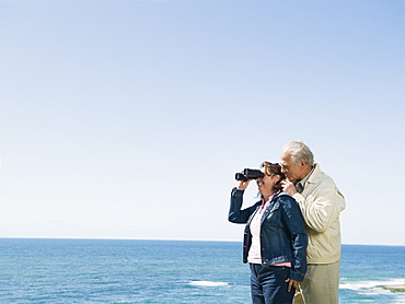 Couple looking at ocean with binoculars