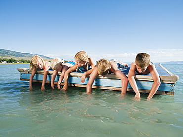 Kids (2-3,6-7,8-9,10-11,12-13) playing on raft on lake