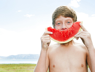 Boy (12-13) eating watermelon