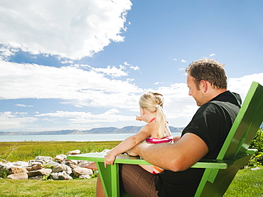 Father and daughter sitting (2-3) on chair and looking at view