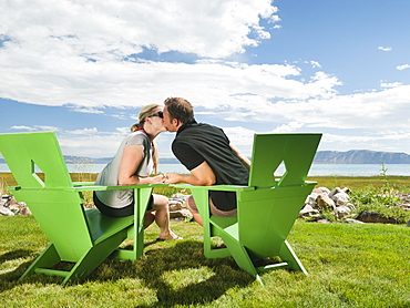 Young couple sitting on meadow and kissing