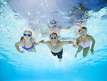 Father with two daughters (6-7,8-9) swimming underwater