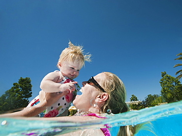 Mother and daughter (12-18months) playing at swimming pool