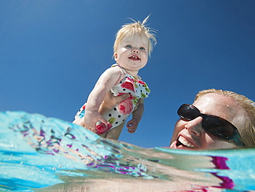 Mother and daughter (12-18months) playing at swimming pool