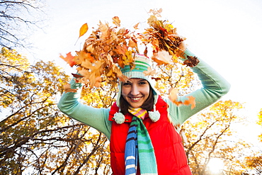 Portrait of smiling young woman throwing dry leaves in autumn forest, Alpine, Utah