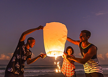 Young people with illuminated lantern on beach