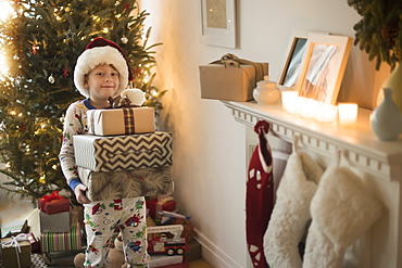 Portrait of boy (6-7) wearing santa claus hat and carrying presents