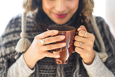 Young woman holding mug with hot drink