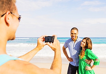 Young man taking photo of couple on beach, Jupiter, Florida