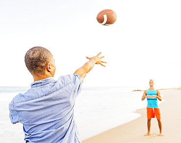 Young men playing football on beach, Jupiter, Florida