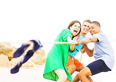 Young people pulling rope on beach