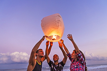 Young people with illuminated lantern on beach