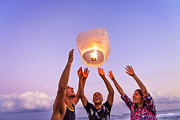 Young people with illuminated lantern on beach