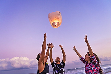 Young people with illuminated lantern on beach