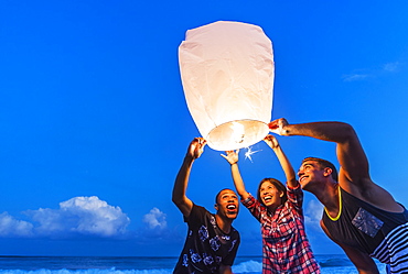 Young people with illuminated lantern on beach