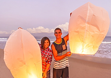 Young people with illuminated lanterns on beach