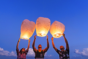 Young people with illuminated lanterns at sunset