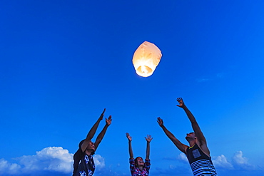 Young people with illuminated lantern at sunset