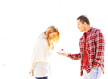 Man giving woman present on beach