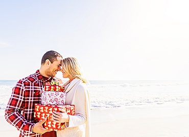 Smiling couple holding presents on beach, Jupiter, Florida