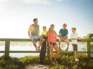 Family with three children (6-7, 10-11, 14-15) talking on beach, Laguna Beach, California