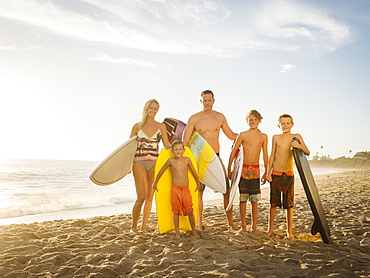 Portrait of family with three children (6-7, 10-11, 14-15) with surfboards on beach, Laguna Beach, California