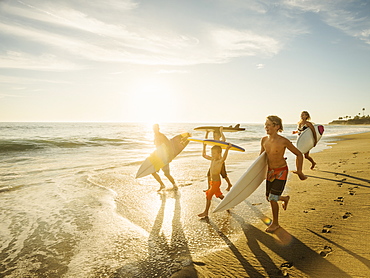 Family with three children (6-7, 10-11, 14-15) with surfboards on beach, Laguna Beach, California