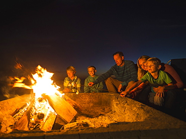 Family with three children (6-7, 10-11, 14-15) cooking marshmallows, Laguna Beach, California