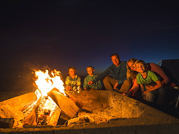 Portrait of family with three children (6-7, 10-11, 14-15) cooking marshmallows, Laguna Beach, California