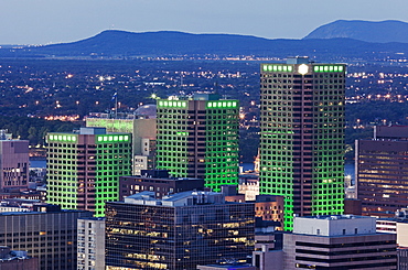 Three skyscrapers illuminated with green light towering over cityscape, Quebec, Canada