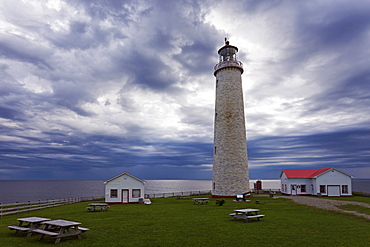 Lighthouse in green camping ground against clouded sky, Quebec, Canada