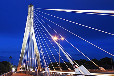 Tower and cables of illuminated Swietokrzyski Bridge against night sky, Poland