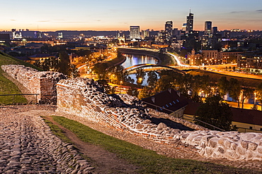 Illuminated riverfront cityscape seen from elevation on opposite bank, Lithuania