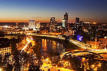 Illuminated riverfront cityscape seen from elevation on opposite bank, Lithuania