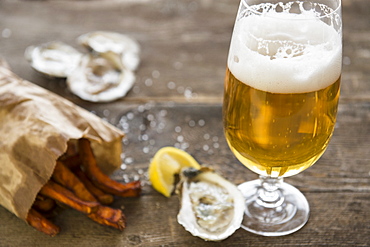 Studio shot of glass of beer, oysters and french fries