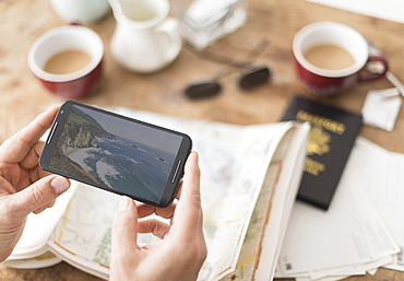 Close up of man's hand holding smartphone above map