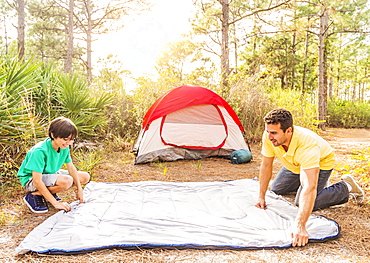 Father and son (12-13) preparing sleeping bag for camping, Jupiter, Florida